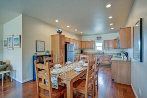 A spacious kitchen with wooden cabinets, a dining table set for four, and a refrigerator.