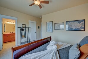 A bedroom with a bed, a ceiling fan, a bathroom with a sink and mirror, and a map on the wall.