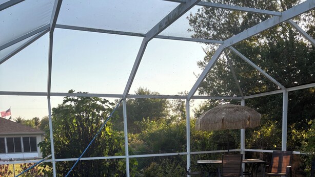 Et overdækket poolområde med patio, stole og et bord.