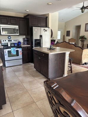 A kitchen with dark wooden cabinets, stainless steel appliances, and a tiled floor. - 3-bedroom house in Rotonda West  golfing, beaches, fishing, shopping, Disney (Rotonda West)