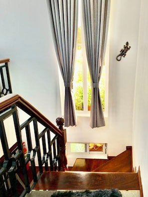 Eine Treppe mit Holzwerteln und einem Fenster mit Vorhängen.