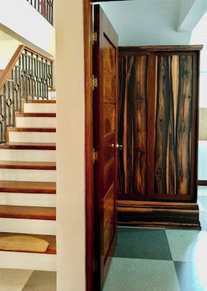 Eine Treppe mit Holzbodenstufen und Metallgeländer, die zu einem Raum mit einem großen Holzschrank führt.