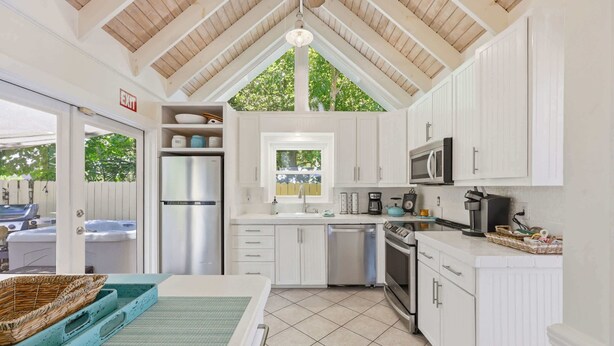 A kitchen with white cabinets, a microwave, a refrigerator, and a sink. - Porch on Pine Downtown (St. Augustine)