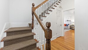A staircase with wooden balusters and carpeted steps leading to a white door. - Porch on Pine Downtown (St. Augustine)