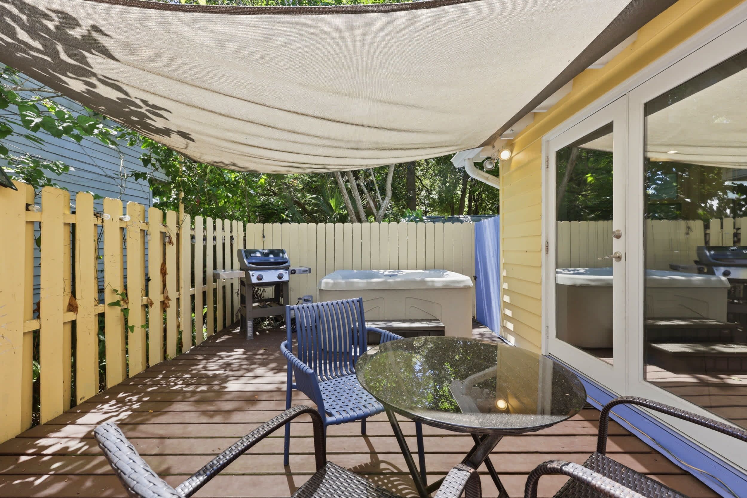 A patio with a table, chairs, a grill, and a hot tub.