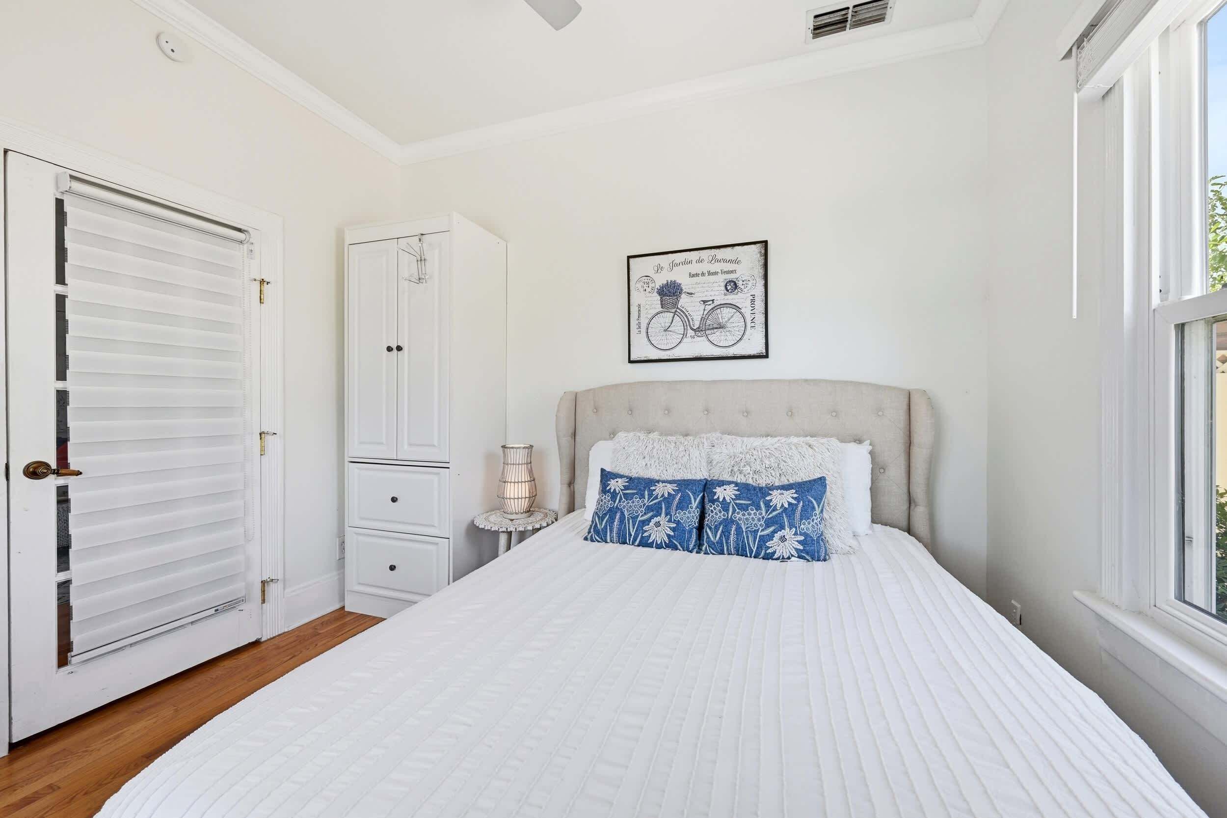 Une chambre à coucher avec un lit, une armoire, une table de chevet et une fenêtre.