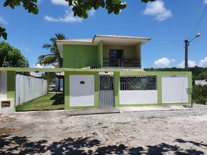 A two-story house with a green and white exterior, a gated entrance, and a visible balcony. - CASA 4 QUARTOS (Porto Seguro)