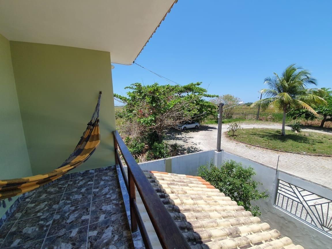 A staircase with a hammock, leading to a balcony overlooking a garden with palm trees.