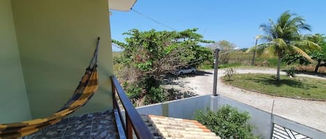 A staircase with a hammock, leading to a balcony overlooking a garden with palm trees.