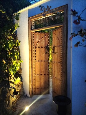 A wooden gate with decorative metalwork, a white wall, and a plant with green leaves. - A CONTEMPORARY VILLA WITH AN EXCEPTIONAL PANORAMA (La Croix-Valmer)