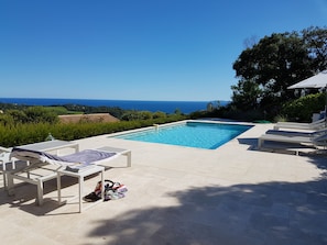 A rectangular swimming pool with lounge chairs and a table, surrounded by a tiled patio. - A CONTEMPORARY VILLA WITH AN EXCEPTIONAL PANORAMA (La Croix-Valmer)