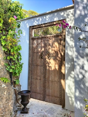 A wooden gate with decorative metalwork, a stone wall, and a potted plant beside it. - A CONTEMPORARY VILLA WITH AN EXCEPTIONAL PANORAMA (La Croix-Valmer)