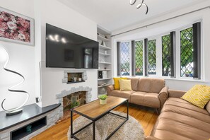 A modern living room with a flat-screen TV, a stone fireplace, a sofa, and a coffee table. - Elegant 3 bedroom | 2 Bath | In Burnley (Lancashire)