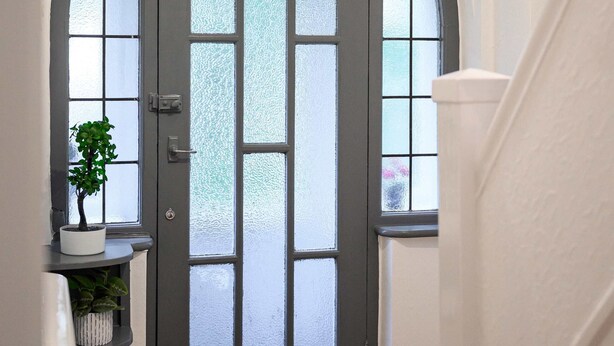 A grey arched door with frosted glass panels, a potted plant on a shelf, and a hanging light fixture. - Elegant 3 bedroom | 2 Bath | In Burnley (Lancashire)