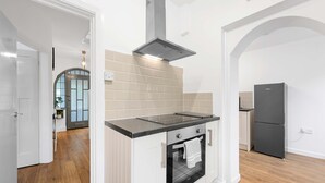 A modern kitchen with a built-in oven, a stainless steel range hood, and a black refrigerator. - Elegant 3 bedroom | 2 Bath | In Burnley (Lancashire)