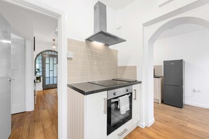 A modern kitchen with a built-in oven, a stainless steel range hood, and a black refrigerator. - Elegant 3 bedroom | 2 Bath | In Burnley (Lancashire)