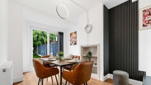 A dining area with a wooden table, two brown chairs, a white radiator, and a black wall with vertical lines. - Elegant 3 bedroom | 2 Bath | In Burnley (Lancashire)