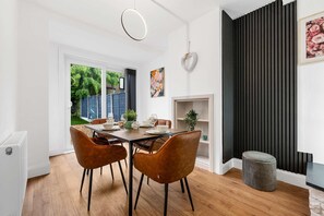 A dining area with a wooden table, two brown chairs, a white radiator, and a black wall with vertical lines. - Elegant 3 bedroom | 2 Bath | In Burnley (Lancashire)