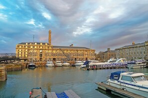A marina with boats docked, a large building with arched windows, and a clear sky. - Luxury studio accommodation, located in historic Royal William Yard, Plymouth. (Plymouth)