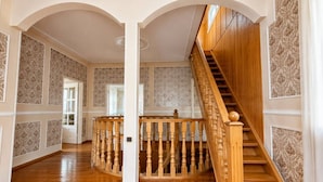 A grand hallway with a wooden staircase, white columns, and patterned wallpaper. - Spacious Forest Guesthouse in Vanadzor for Families & Groups (Vanadzor)