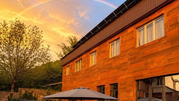 A modern building with a patio area featuring a table and bench, a covered seating area, and a staircase leading to the entrance. - Spacious Forest Guesthouse in Vanadzor for Families & Groups (Vanadzor)