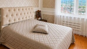 A bedroom with a large bed, a wooden floor, a window with a view, and a ceiling light. - Spacious Forest Guesthouse in Vanadzor for Families & Groups (Vanadzor)