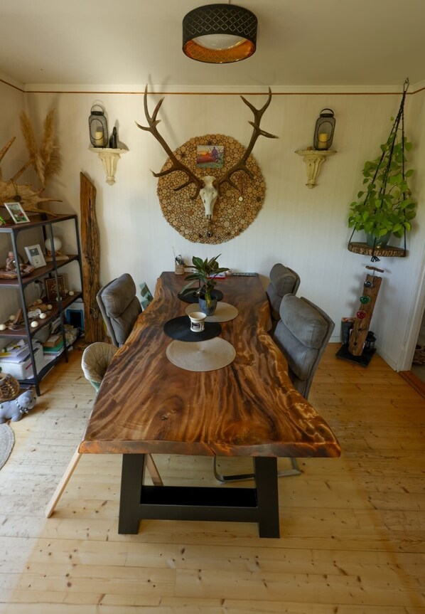 A dining area with a large wooden table, chairs, a wall-mounted deer skull decoration, and a hanging plant. - A Swedish-style house with horses and a canoe trail right outside the door (Värmland County)