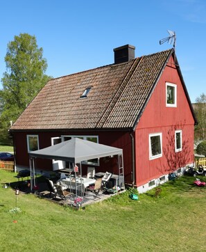 A red barn with a sloped roof, a covered patio with outdoor furniture, and a small window. - A Swedish-style house with horses and a canoe trail right outside the door (Värmland County)