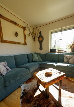 A living room with a sectional sofa, a wooden coffee table, a wall clock, and a window with a view. - A Swedish-style house with horses and a canoe trail right outside the door (Värmland County)