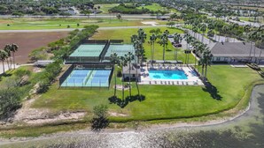 Een resort met meerdere tennisbanen, een zwembad en een ruime parkeerplaats.