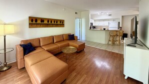 A living room with a sofa, a round coffee table, and a painting on the wall. - Peaceful Beachwalk Escape! Updated 3rd-Floor Condo w/ Lanai, Pool & Hot Tub (Fort Myers)