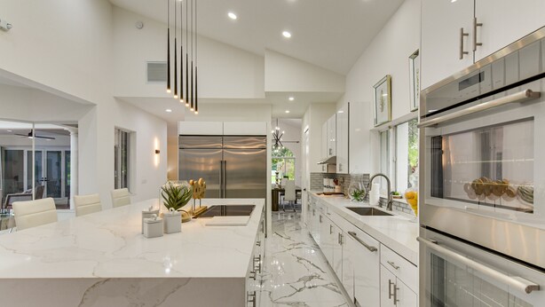 A modern kitchen with a marble countertop, stainless steel appliances, and a central island.