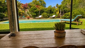 A wooden table with chairs, a potted plant, and a view of a swimming pool and garden. - Provençal villa with pool, ocean views, and walking distance to the beach, sleeps 10, Giens Peninsula (Hyères)