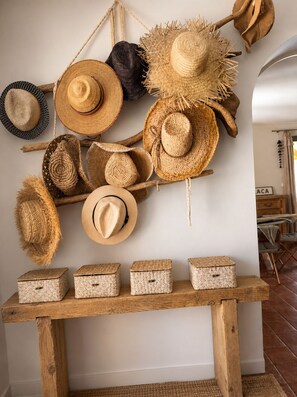 A variety of woven hats and woven baskets displayed on a wooden shelf and wall.