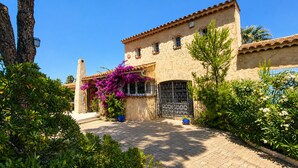 A building with a tiled roof, a stone facade, and a gate with a metal design. - Provençal villa with pool, ocean views, and walking distance to the beach, sleeps 10, Giens Peninsula (Hyères)