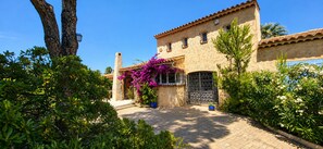 A building with a tiled roof, a stone facade, and a gate with a metal design.