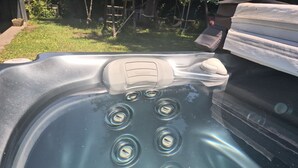 Ett bubbelbadkar med flera justerbara munstycken, en kontrollpanel och en kudde.