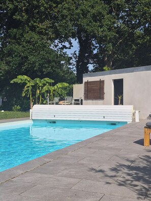 A swimming pool with a modern design, surrounded by a paved area and a building with a minimalist facade. - Villa with pool and spa in Anglet for 8-10 people (Anglet)