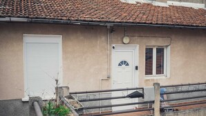 A building with a tiled roof, a white door, and a window. - 2-room apartment with air field hockey arcade machine and computer (Vitry-sur-Seine)