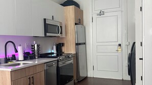 Une cuisine moderne dotée d’un four, d’un micro-ondes et d’un réfrigérateur encastrés, de meubles de rangement en bois et d’une porte blanche.