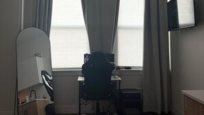 Une pièce comprenant un bureau, une chaise et un téléviseur fixé au mur.