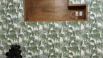 A room with a wooden shelf unit mounted on a wall with a tropical leaf pattern wallpaper.