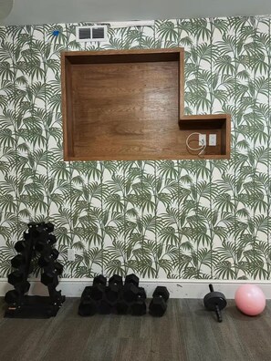 A room with a wooden shelf unit mounted on a wall with a tropical leaf pattern wallpaper.