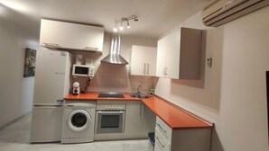 A compact kitchen with a washing machine, oven, microwave, and a sink.