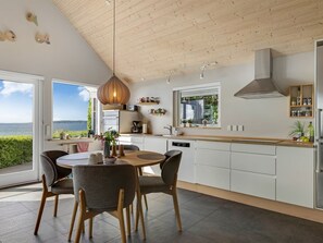 Eine moderne Küche mit Essbereich, großen Fenstern und Meerblick.