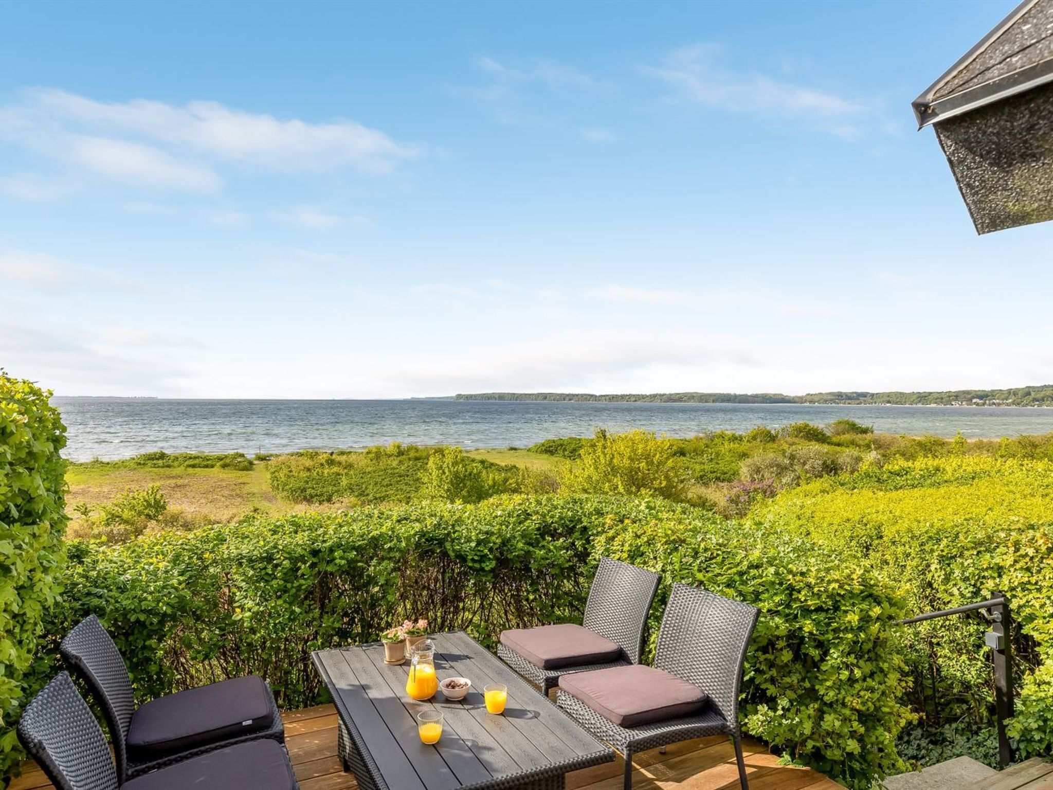 A patio with a table and chairs overlooking a body of water.