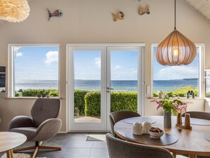 Ein Zimmer mit Meerblick, einem Esstisch mit Stühlen und einer Pendelleuchte.