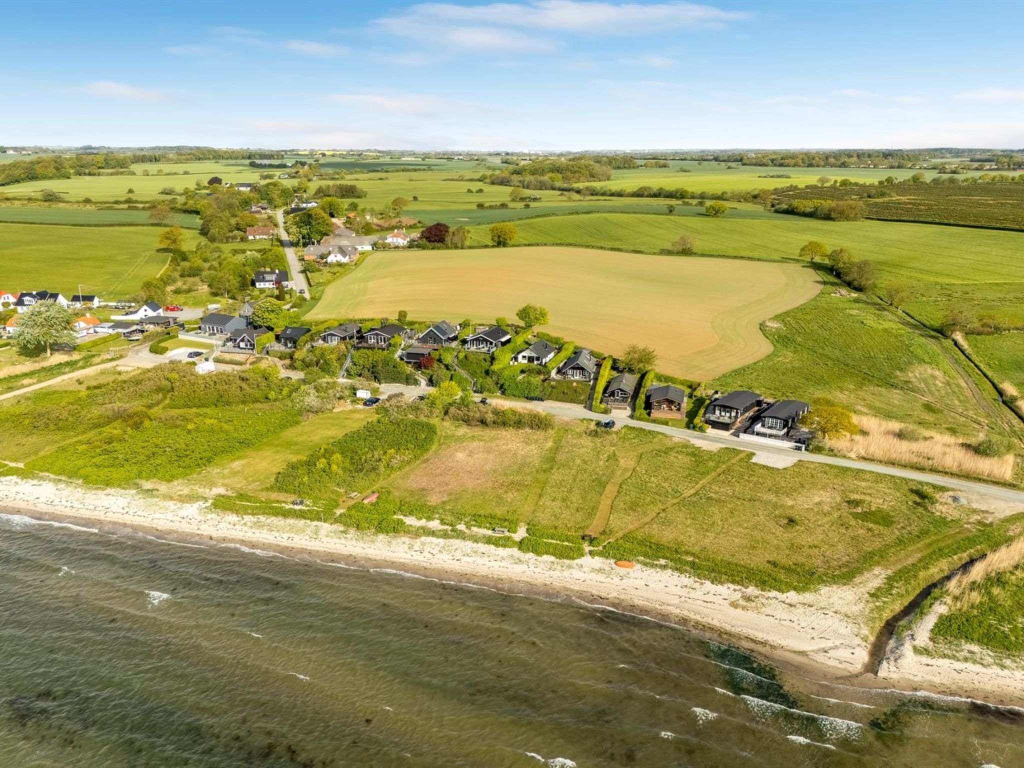 Vista aérea de una zona residencial costera con casas, un campo de golf y una playa.