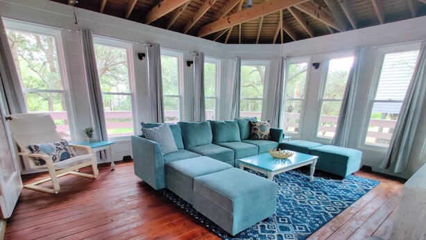 A room with a wooden floor, a sectional sofa, a small table, and a chair.
