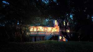A two-story house with a balcony, surrounded by trees.
